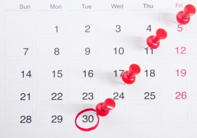 Calendar with tax deadline circled and marked with red pushpins