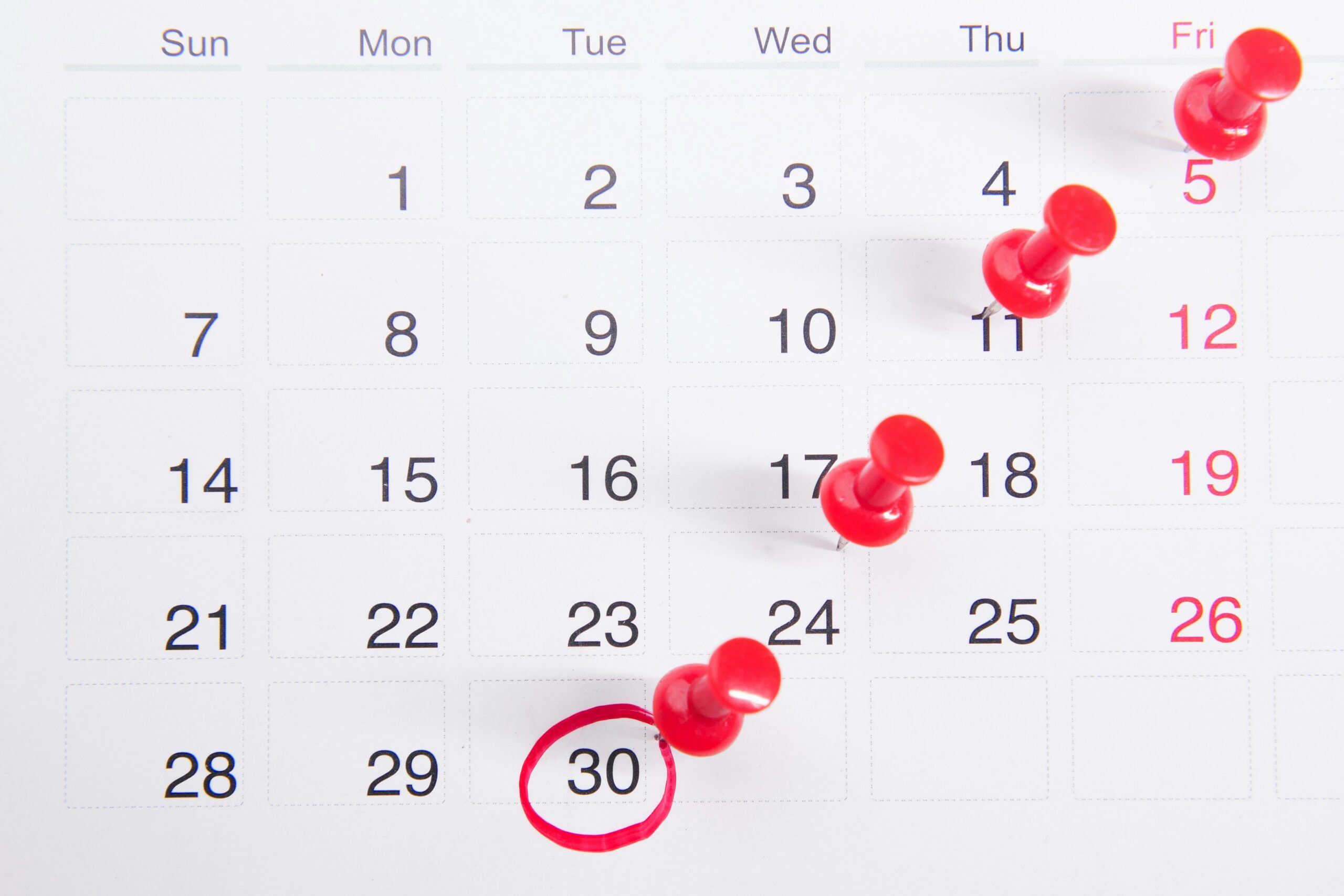 Calendar with tax deadline circled and marked with red pushpins